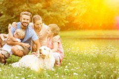 Glückliche Familie mit Kinder und Hund zusammen im Garten im Sommer