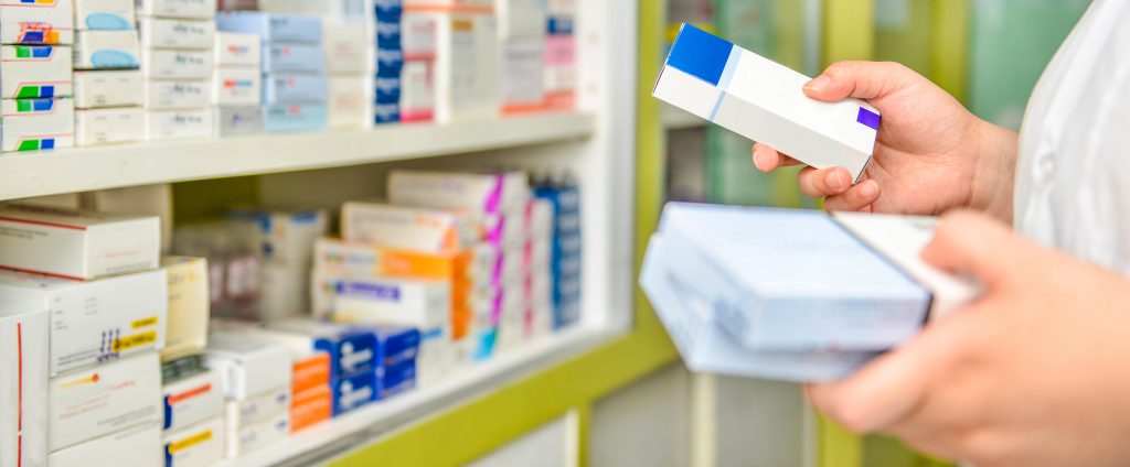 Pharmacist holding medicine box in pharmacy drugstore.